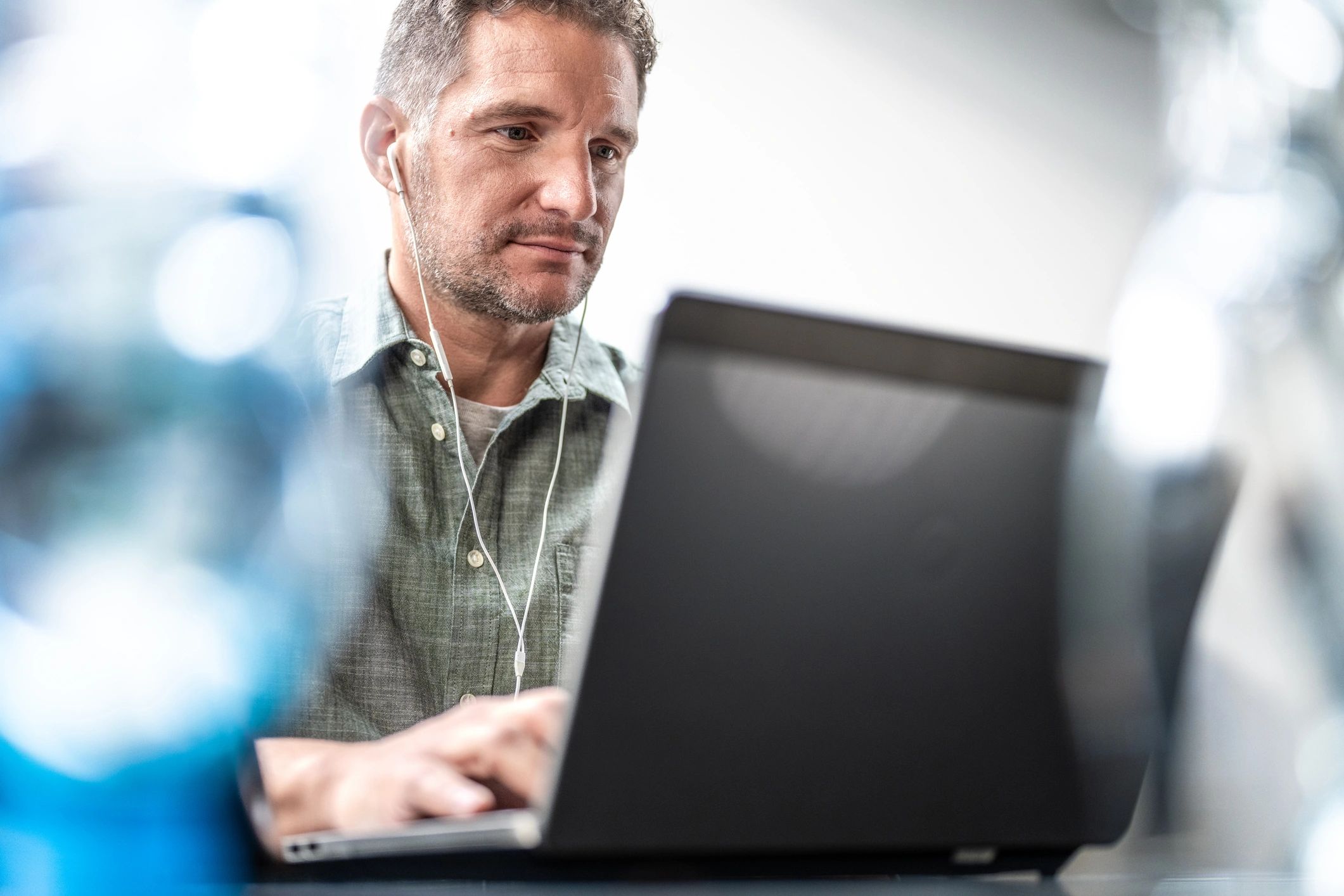 Man in earphones working on laptop in office